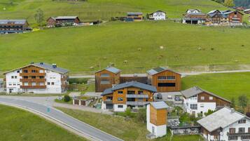 Un pueblo rural con casas de madera tradicionales, una carretera y ganado pastando.