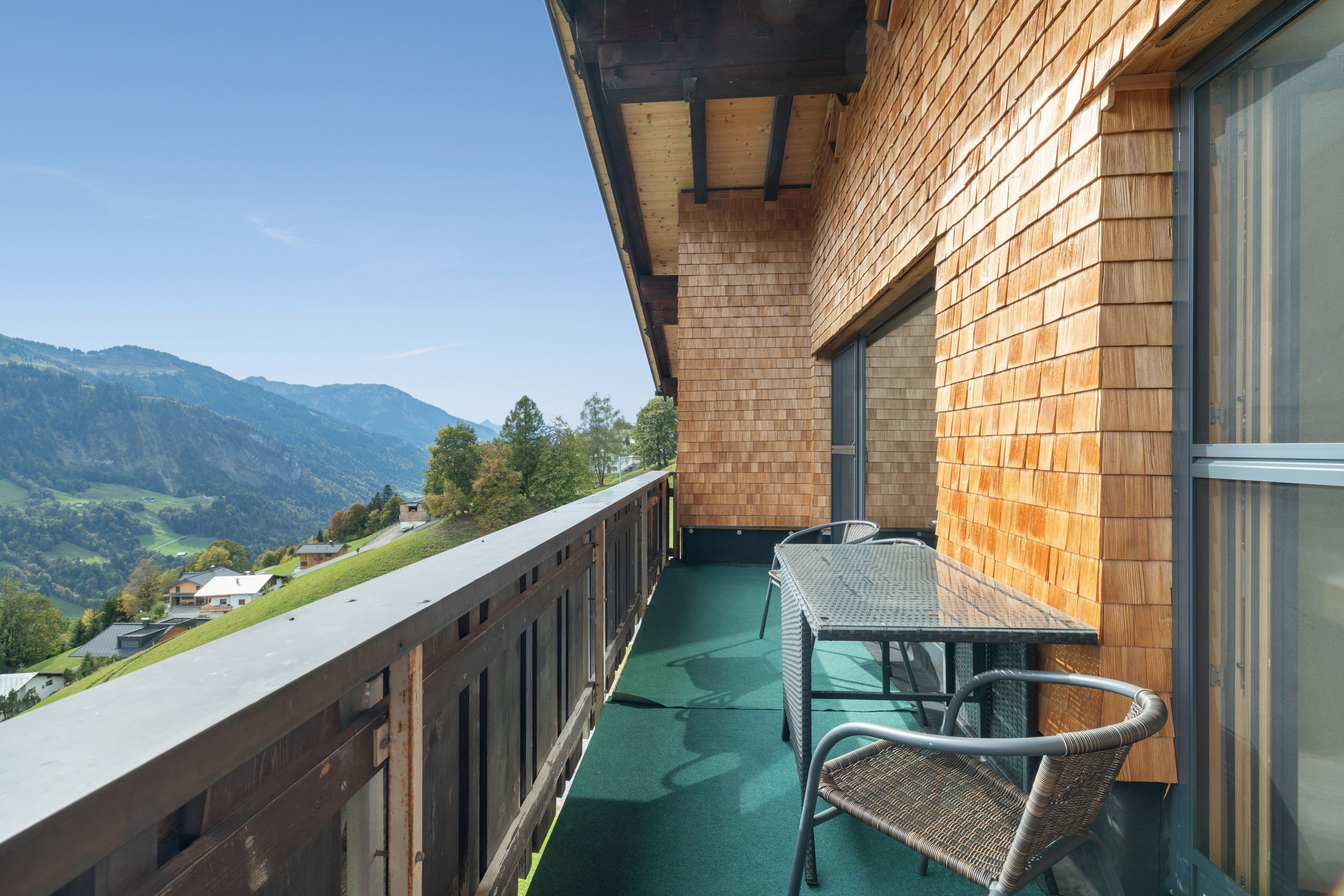 Ein Balkon mit Blick auf Berge, einem Tisch und Stühlen.
