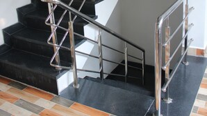 Una escalera con barandilla de metal y escalones negros.