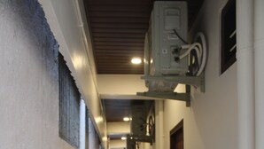 Un pasillo con suelo a cuadros, pared blanca y una puerta a la derecha.