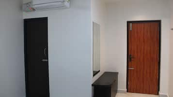 A room with a black door, a wooden door, a white wall, and a small black table.