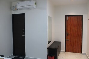 Um quarto com porta preta, porta de madeira, parede branca e uma pequena mesa preta.