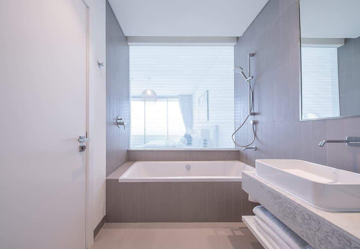 Un baño moderno con bañera, un espejo grande y una ventana.