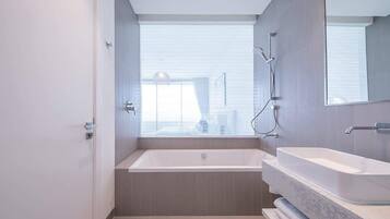 Un baño moderno con bañera, un espejo grande y una ventana.