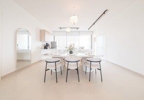 Una cucina moderna con isola centrale, sgabelli da bar, illuminazione a sospensione e vista sul lato sinistro.