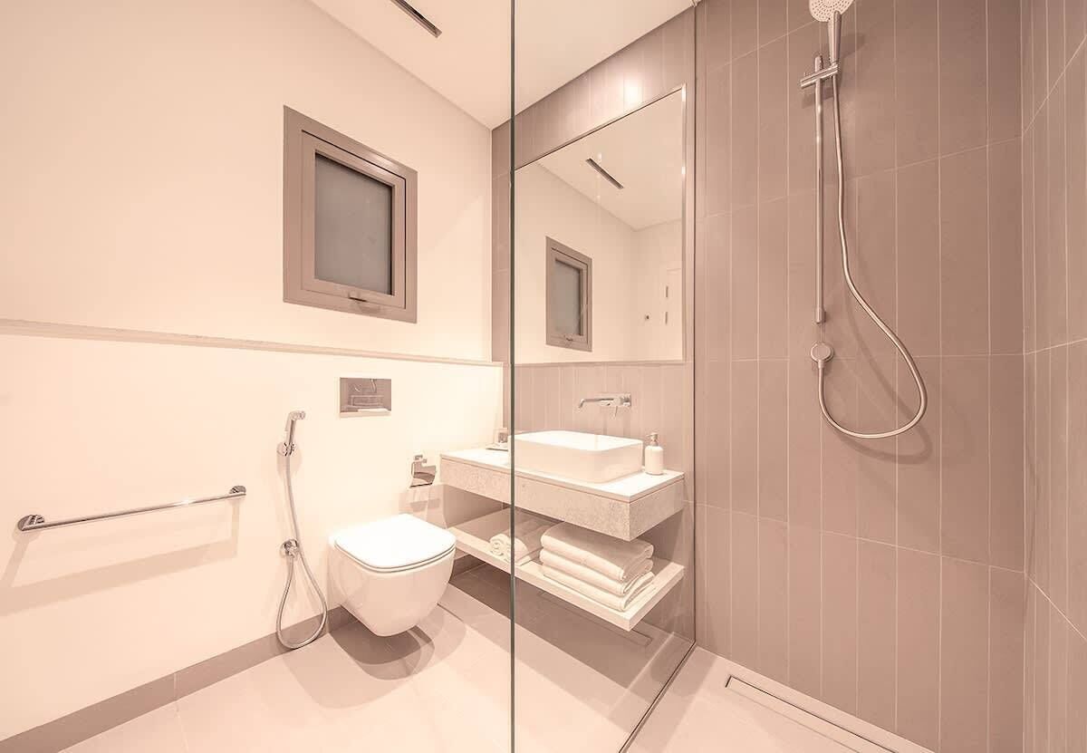 Een moderne badkamer met een douchecabine van glas, een toilet, een wastafel en een handdoekrek.