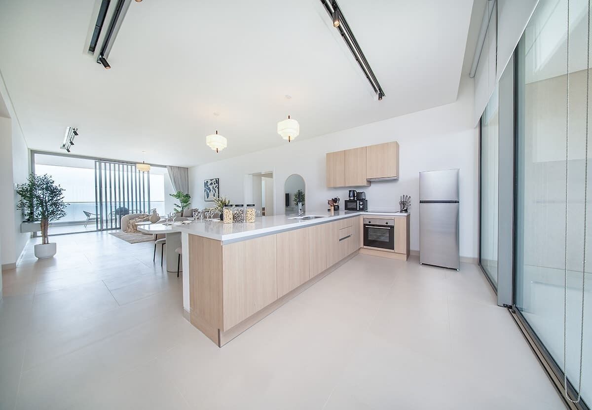 A modern kitchen with a central island, built-in appliances, and a large window providing natural light.