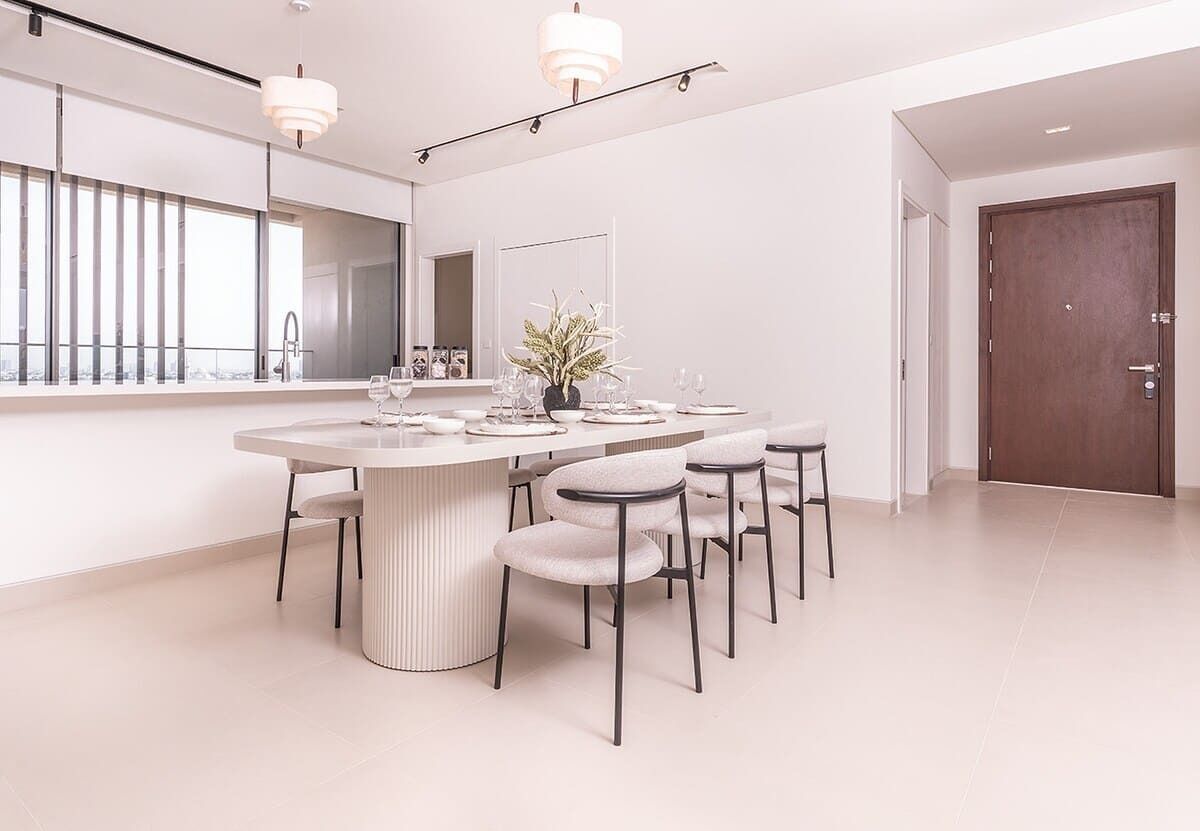 Uma sala de jantar moderna com uma mesa redonda, seis cadeiras e um vaso de planta.