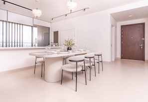 A modern dining area with a round table, six chairs, and a potted plant.