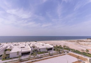 A coastal hotel with a modern architectural design, featuring a rooftop pool area and a view of the beach. - Seaside Hills Apartment W Sea Views & Pool Access (Ajman)