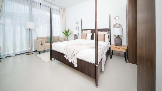 Ein modernes Schlafzimmer mit einem Himmelbett, einem Nachttisch mit Lampe, einem Holzbeistelltisch, einem großen Fenster mit durchsichtigen Vorhängen und einer Blumentopf-Pflanze.