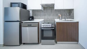 A compact kitchen with a refrigerator, microwave, dishwasher, stove, and sink.