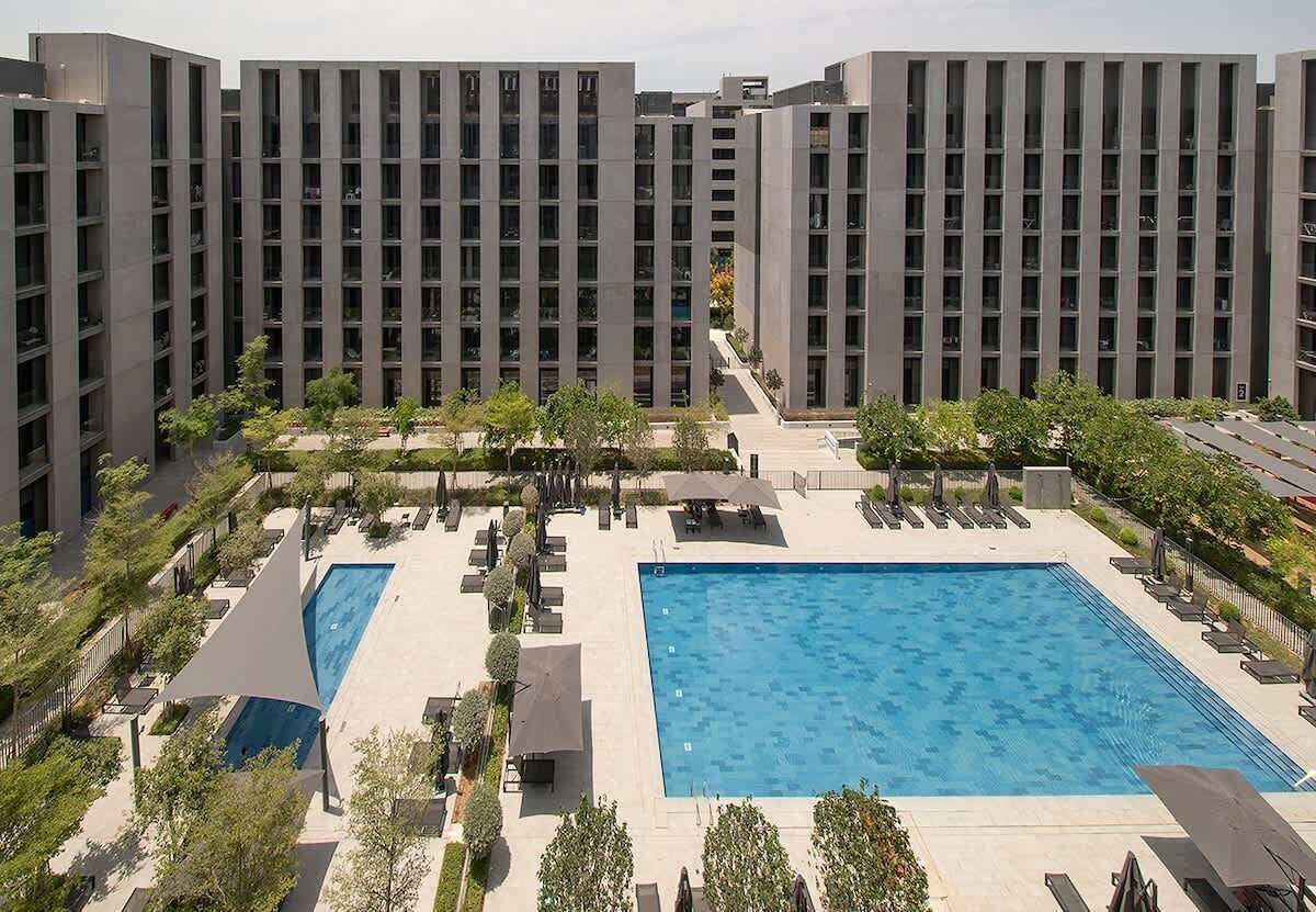 Un hôtel moderne doté d’une piscine centrale, entourée d’espaces de détente et de verdure.