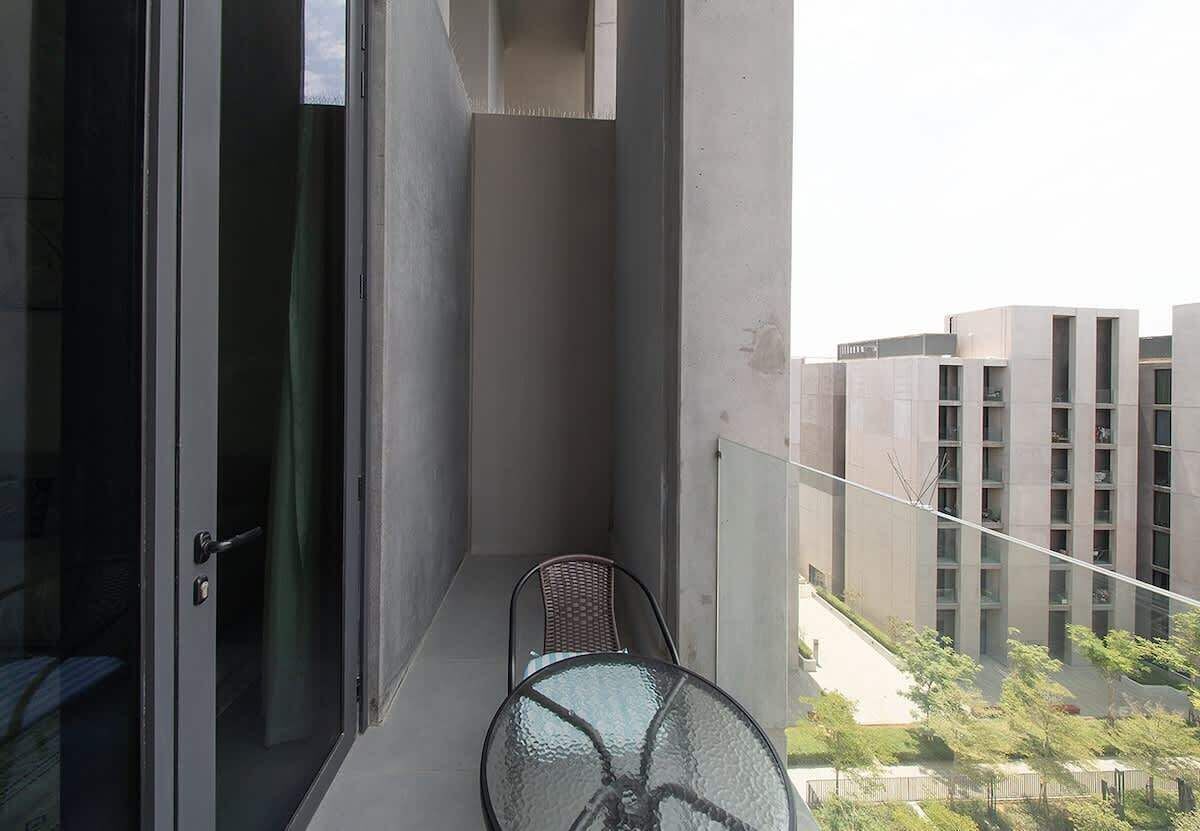 A balcony with a glass door, a chair, and a table.