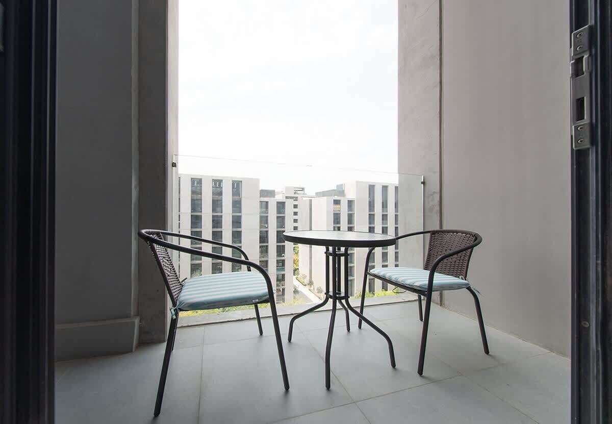 A balcony with two chairs and a small table, overlooking a cityscape.