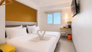 A hotel room with a bed, a desk, a chair, a trash bin, and a TV mounted on the wall. - d'primahotel Malioboro Yogyakarta (Yogyakarta)
