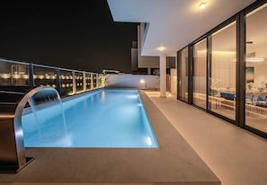 A modern outdoor swimming pool with a glass balustrade, a contemporary interior with a dining area, and a clear view of the surrounding landscape. - Blausee Beachfront Villa with Private Pool (Al Hamriyah)