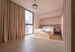 Ein modernes Schlafzimmer mit einem großen Bett, einem Nachttisch und Blick durch eine Schiebetür.