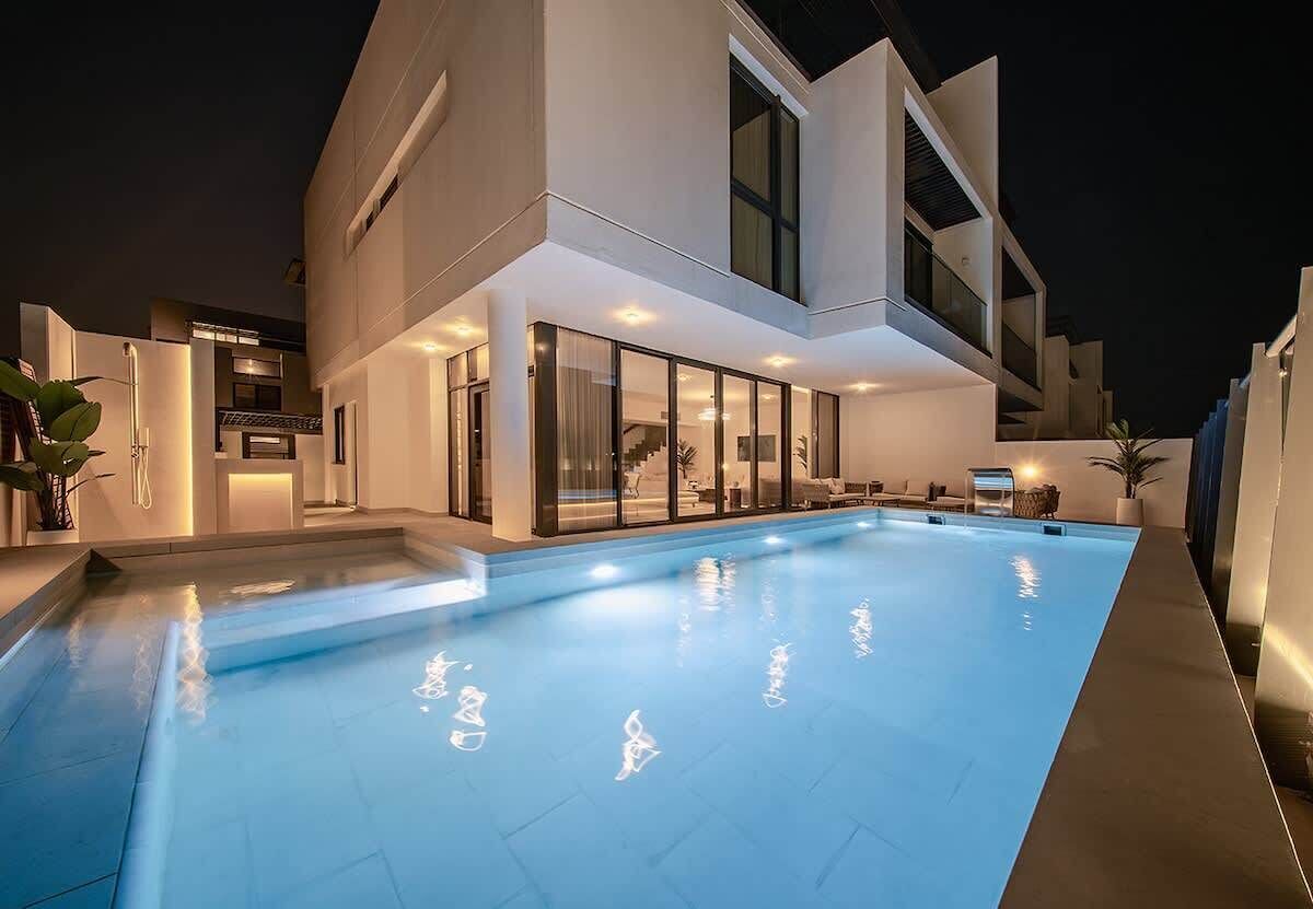 A modern building with a swimming pool, large windows, and outdoor seating.