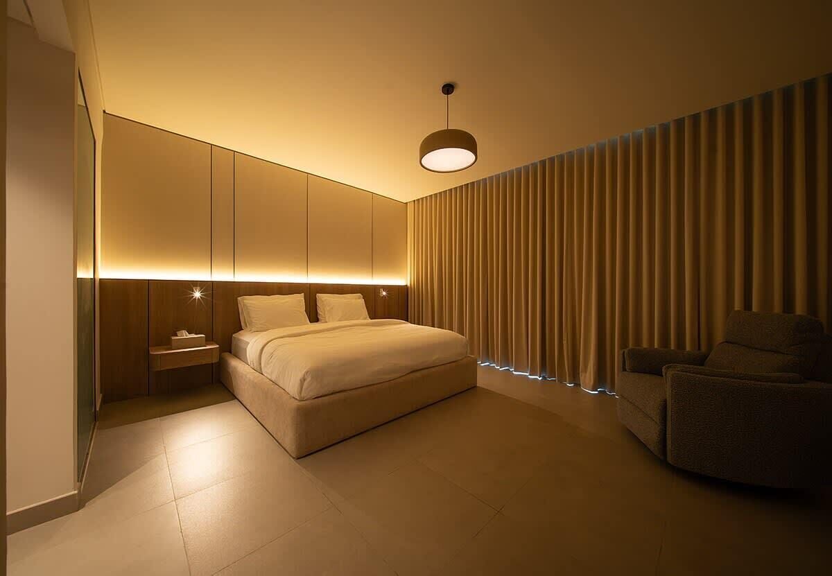 A modern bedroom with a bed, bedside table, and a chair.