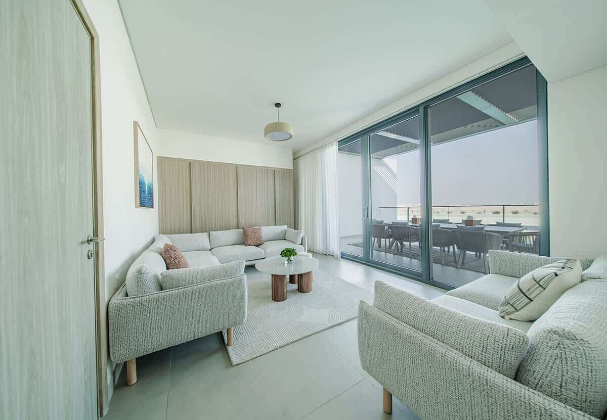 Una sala de estar moderna con un gran ventanal corredizo que da a un espacio exterior.