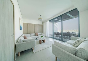 A modern living room with a large sliding glass door leading to an outdoor area. - Blausee Beachfront Villa with Private Pool (Al Hamriyah)