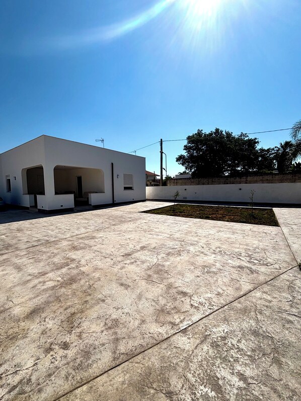 A modern building with a flat roof and a concrete patio area.