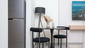 Eine moderne Küche mit einem eingebauten Kühlschrank, einem runden Tisch mit vier Stühlen, einer Stehlampe und einem Bild an der Wand.