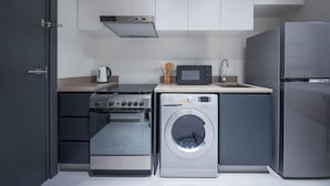Eine kleine Küche mit Herd, Mikrowelle, Backofen, Waschmaschine und Kühlschrank.