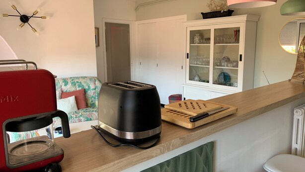 Een keuken met een broodrooster, een snijplank en een kast met glazen deuren.