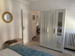 Ein Schlafzimmer mit Bett, Kleiderschrank, Spiegel und Heizkörper.