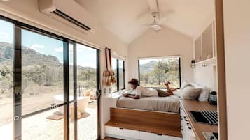 A bedroom with a large sliding glass door, a bed, a ceiling fan, and a view of the outdoors.