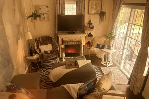 A cozy living room with a fireplace, a television, and a large window with a view.