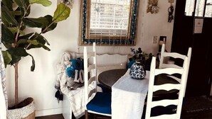 A dining area with a table, chairs, a ceiling fan, a window with blinds, and a potted plant. - Treehouse Retreat with Firepit & Forest Views in Hopkins, South Carolina (Hopkins)