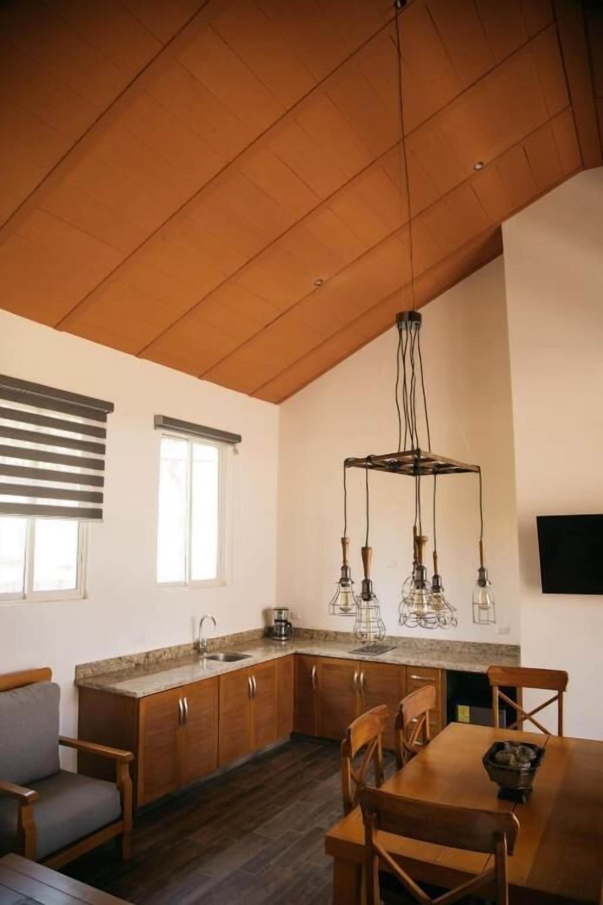 A kitchen with wooden cabinets, a dining table, and a hanging light fixture.