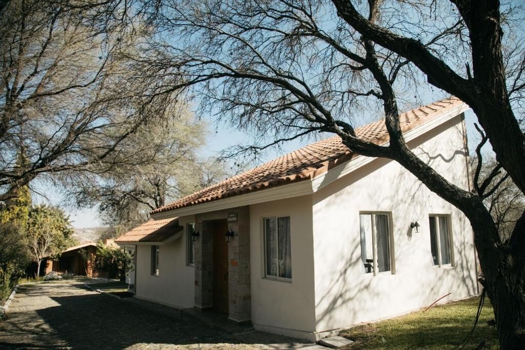 Un edificio de una planta con tejado de baldosas, una puerta principal y ventanas.
