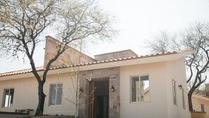 A two-story building with a stone facade, a tiled roof, and a small front yard with a tree. - Montelago Cabañas & Resort (San Juan de los Lagos)