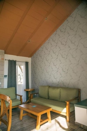 A room with a wooden ceiling, a green sofa, a wooden coffee table, and a patterned wall. - Montelago Cabañas & Resort (San Juan de los Lagos)