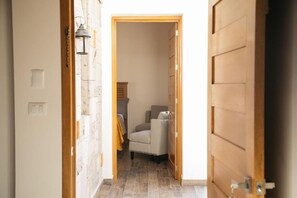 A hallway with a door leading to a room, a lamp, and a chair. - Montelago Cabañas & Resort (San Juan de los Lagos)