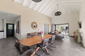 A spacious living area with a large wooden dining table, comfortable seating, a decorative mirror, and a view to the outside. - Penthouse Casa James Mambo Beach Jacuzzi (Willemstad)