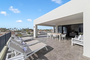 Une terrasse extérieure moderne, aménagée avec des fauteuils de détente, une table à manger et un canapé.