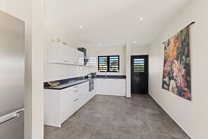 Eine moderne Küche mit weißen Schränken, einer schwarzen Arbeitsplatte und einem großen Fenster.