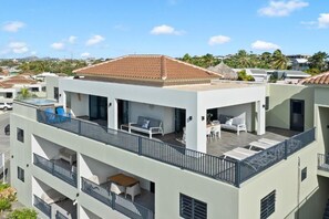 A multi-story building with balconies, outdoor seating, and a swimming pool. - Penthouse Casa James Mambo Beach Jacuzzi (Willemstad)
