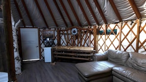 Un interior acogedor con un banco de madera, un sofá, un refrigerador pequeño y un ventilador.