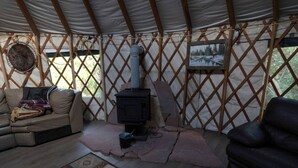 A cozy interior with a sofa, a fireplace, and a patterned rug. - Glamping Yurt with Firepit, Hammock & Wood Stove in Garden Valley, Idaho (Garden Valley)