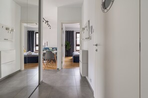 Habitación de hotel moderna con una cama grande, un comedor con mesa y sillas, y una cocina equipada con refrigerador.