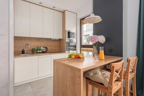 Una cocina moderna con armarios blancos, encimera de madera y horno integrado.