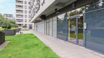 A modern building with a glass facade, a paved walkway, and a small grassy area.