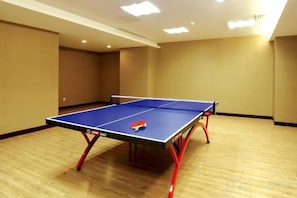 Una mesa de ping pong en una habitación con piso de madera y paredes color crema.