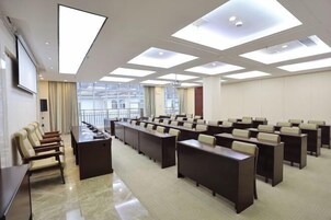 Uma sala de conferências com várias mesas e cadeiras, grandes janelas e teto alto com claraboias.